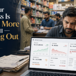 A concerned Pakistani business owner reviews a laptop cash-flow dashboard while staff and customers work in a busy retail store, showing strong sales, overdue invoices, inventory value, and low cash in hand.